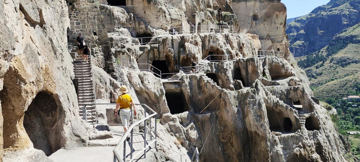 Besucher erkunden die Steintreppen und in den Fels gehauenen Höhlenwohnungen des alten Felsklosters Wardsia in Georgien