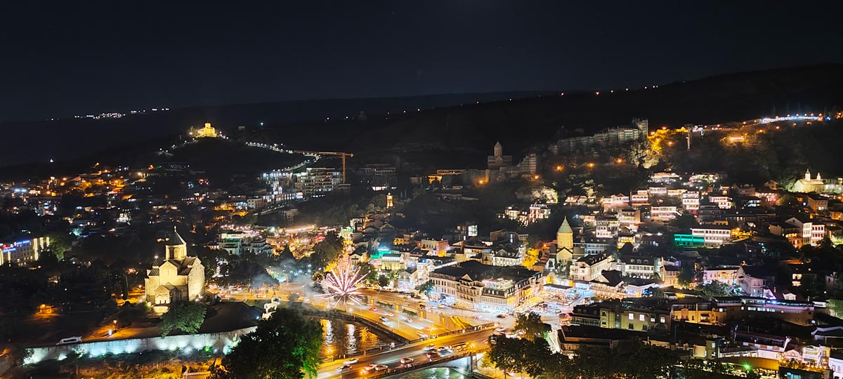 Beleuchtete nächtliche Stadtansicht der Altstadt von Tiflis mit historischen Kirchen und Brücken über den Fluss in Georgien
