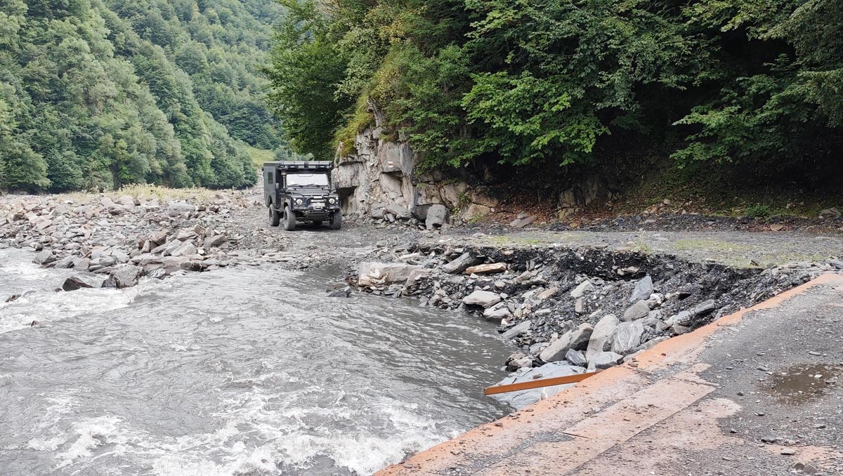 Overland-Fahrzeug überquert einen Flussabschnitt des Schawi Aragwi im Großen Kaukasus, Georgien